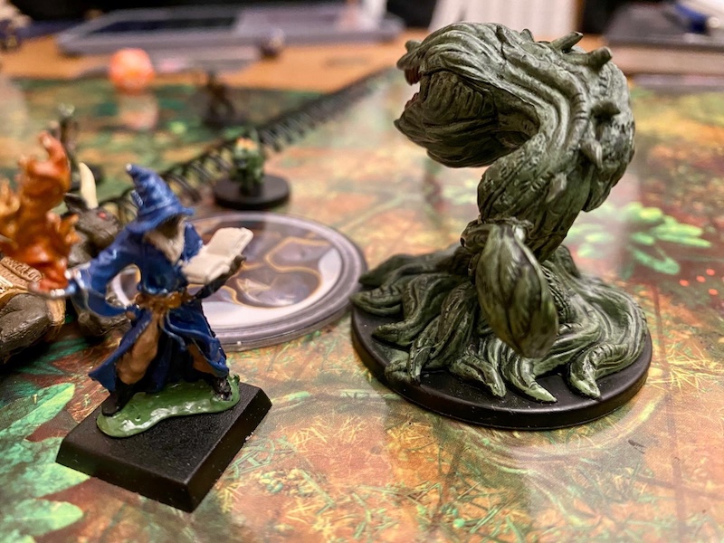 Minis on jungle battle mat. Wizard PC faces off against giant plant monster