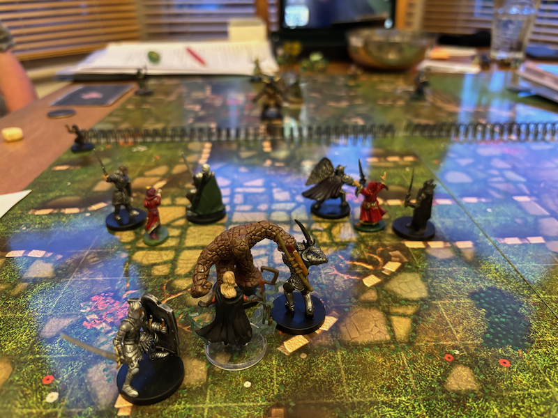 Earth elemental and PC minis on printed battle mat book featuring ruins.
